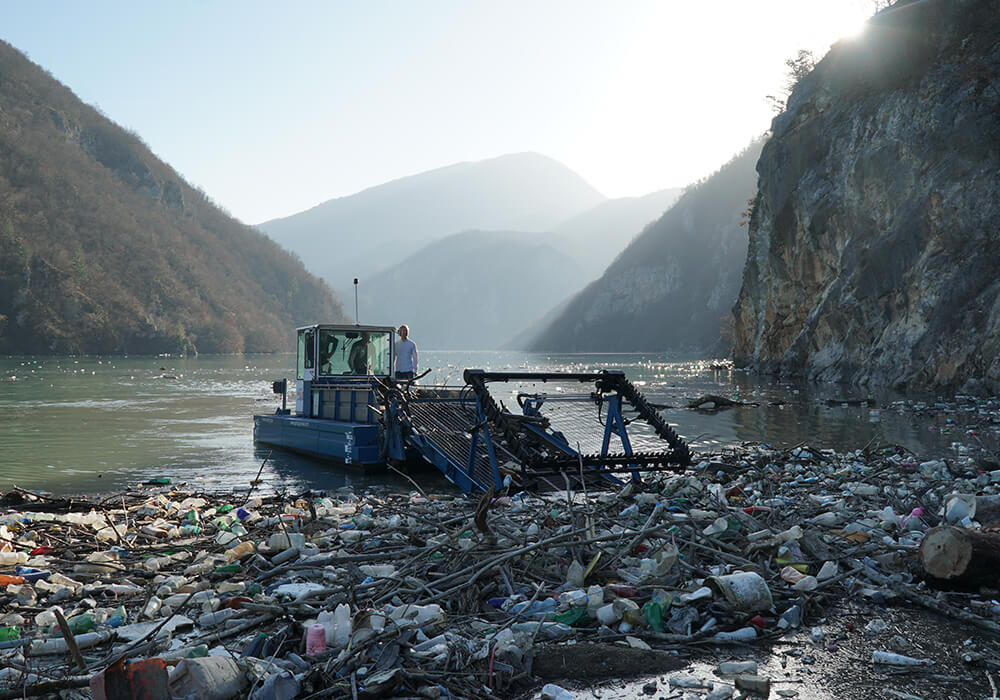 Berky Boot sammelt auf Wasser zwischen Bergen Müll ein