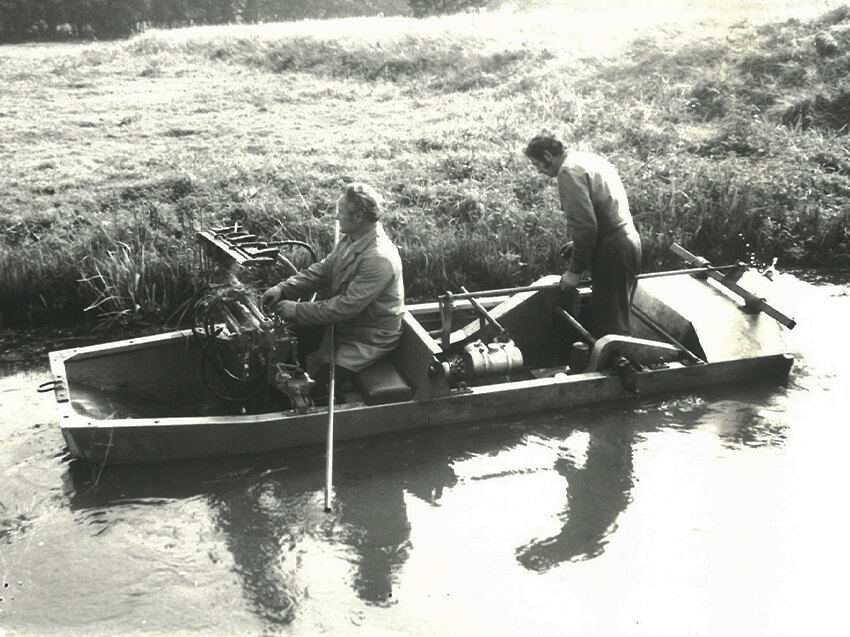 Historie 2 Mitarbeiter im Boot bei Böschungsarbeiten